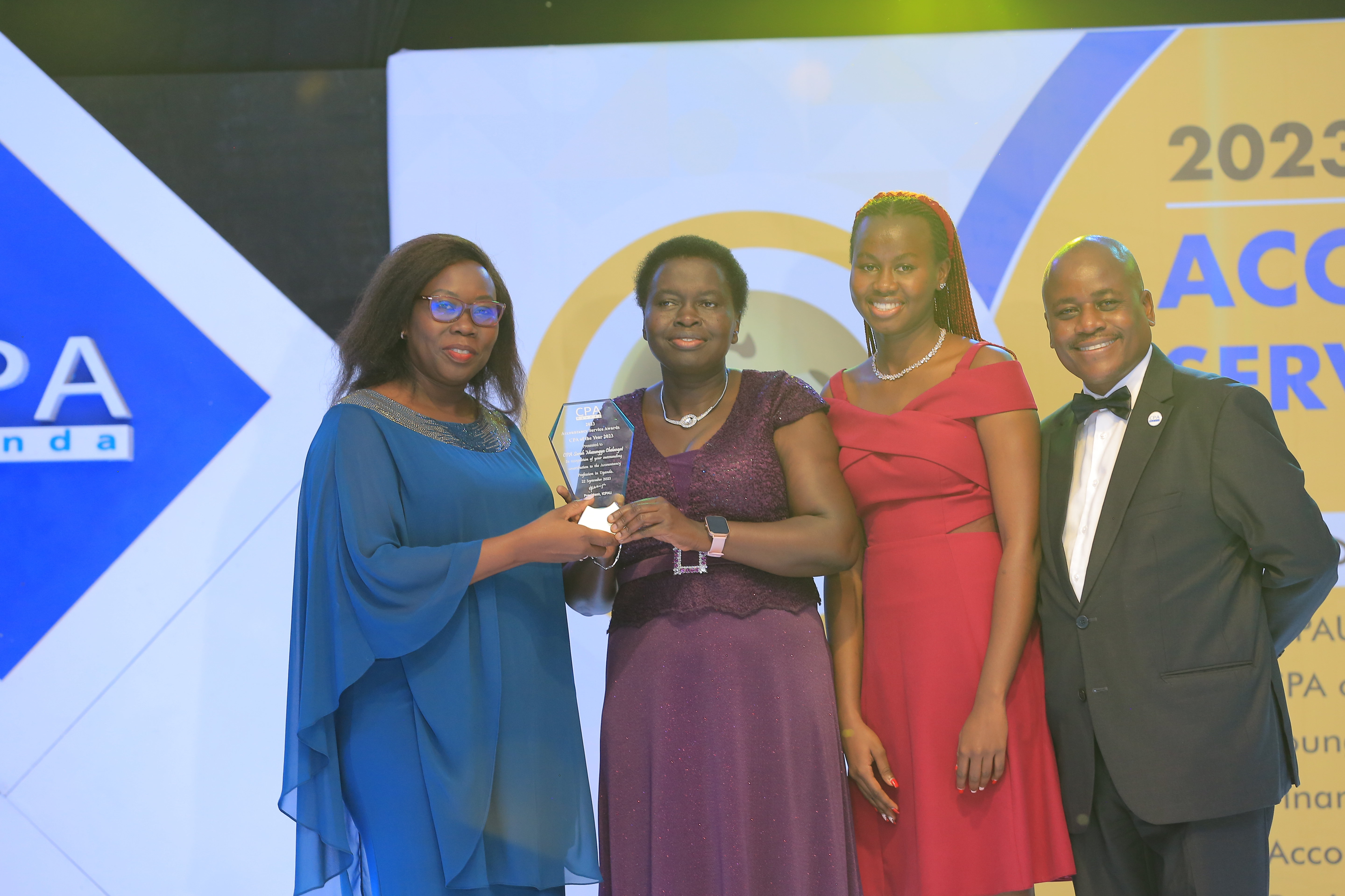 CPA Sarah Chelangat of URA accompanied by her daughter receives an award from CPA Josephine Okui Ossiya, president ICPAU. The extreme right is CPA Ronald Mutumba. (CPA Of the Year Award)