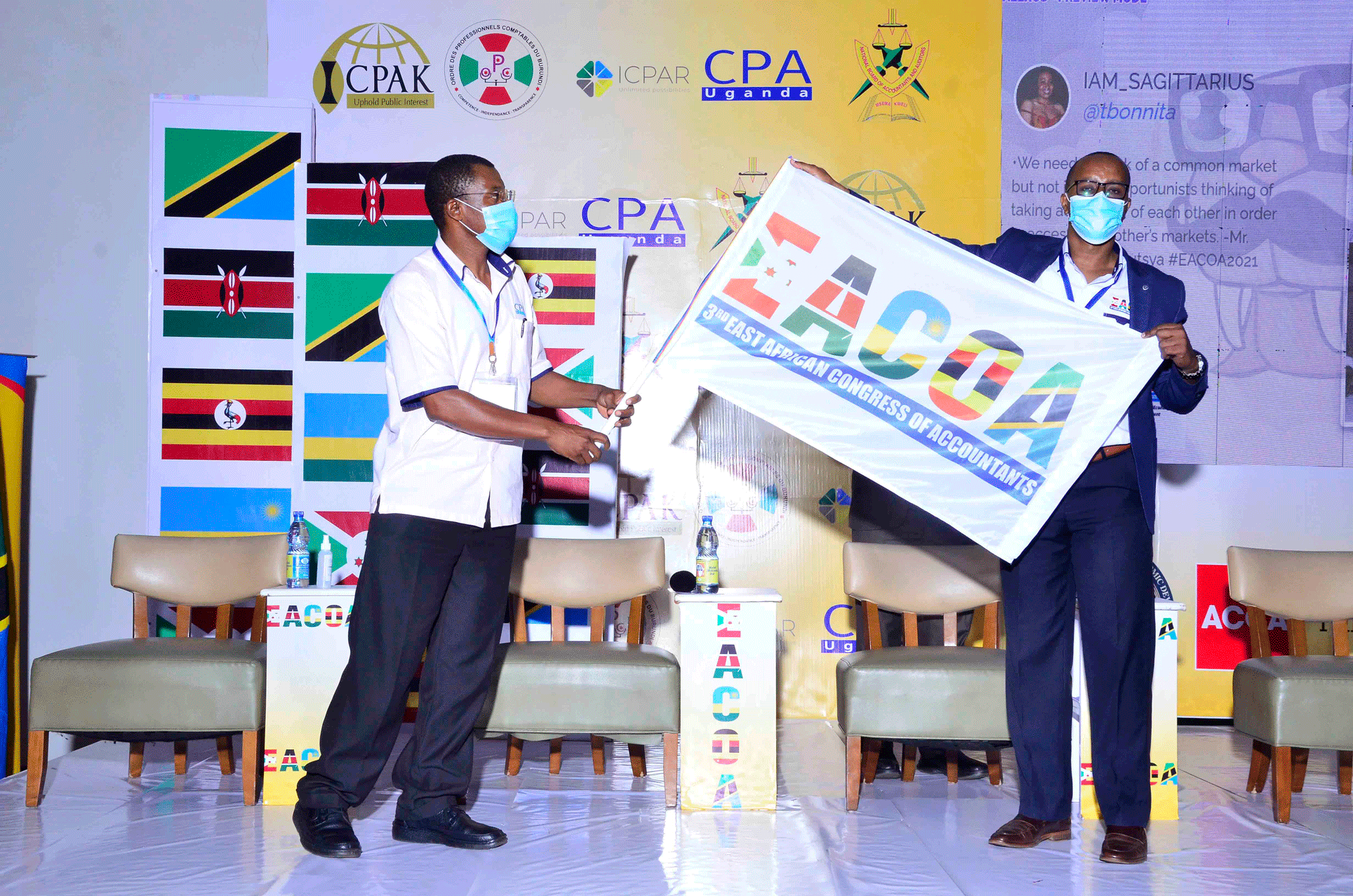 CPA Derick Nkajja hands over an EACOA flag to Mr. Ssali of ICPAR - the next EACOA organisers