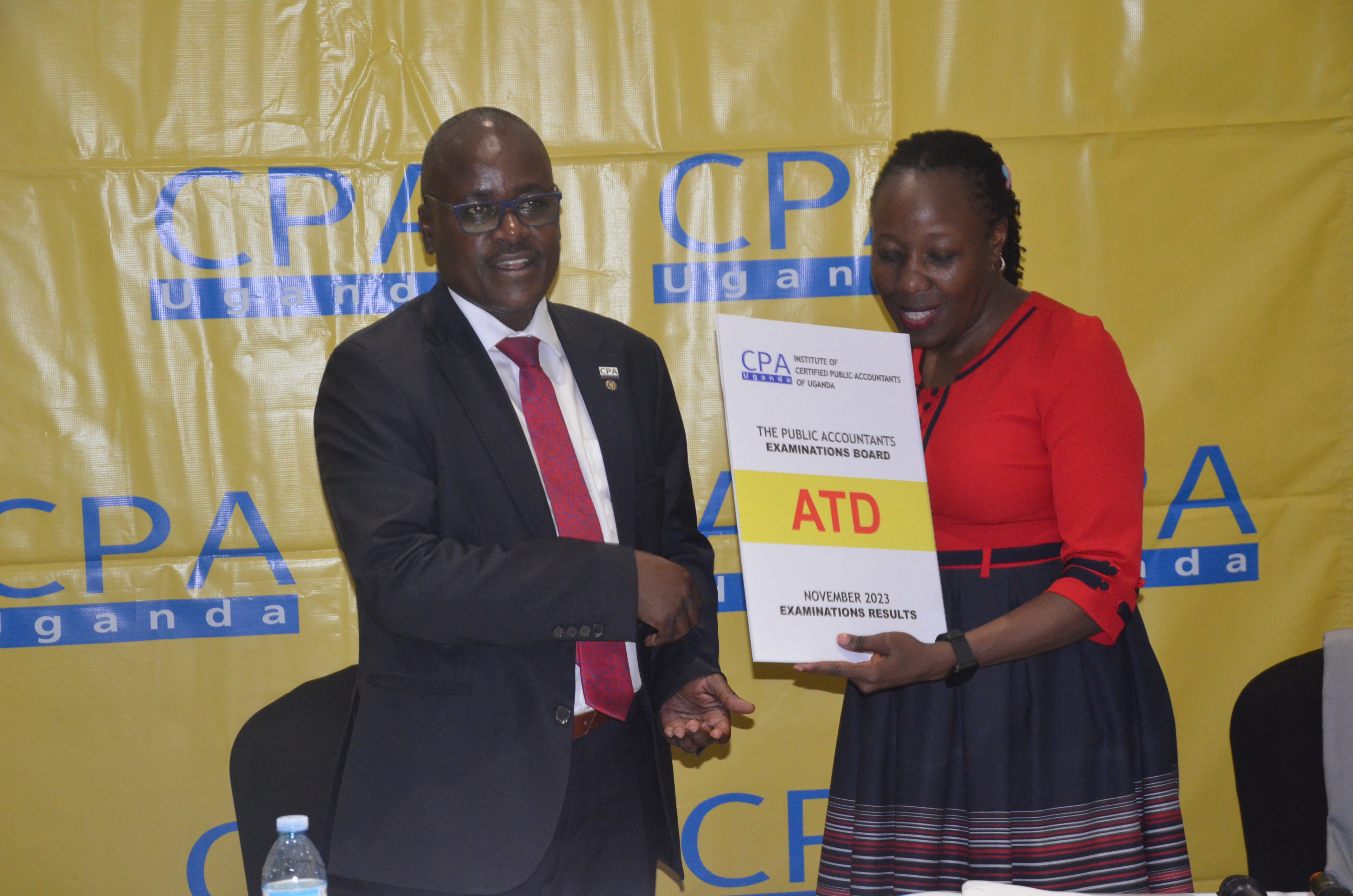 CPA Pro Laura Orobia, Chairperson PAEB  hands over the ATD November Examinations 2023 results to Ronald Mutumba, Vice President of ICPAU.