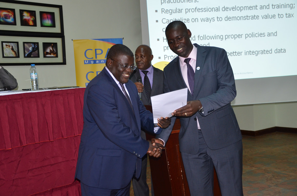 CPA Owekitibwa Dr. Hajji Twaha Kaawaase (L), a practising accountant, receiving a certificate in honour of his presentation.