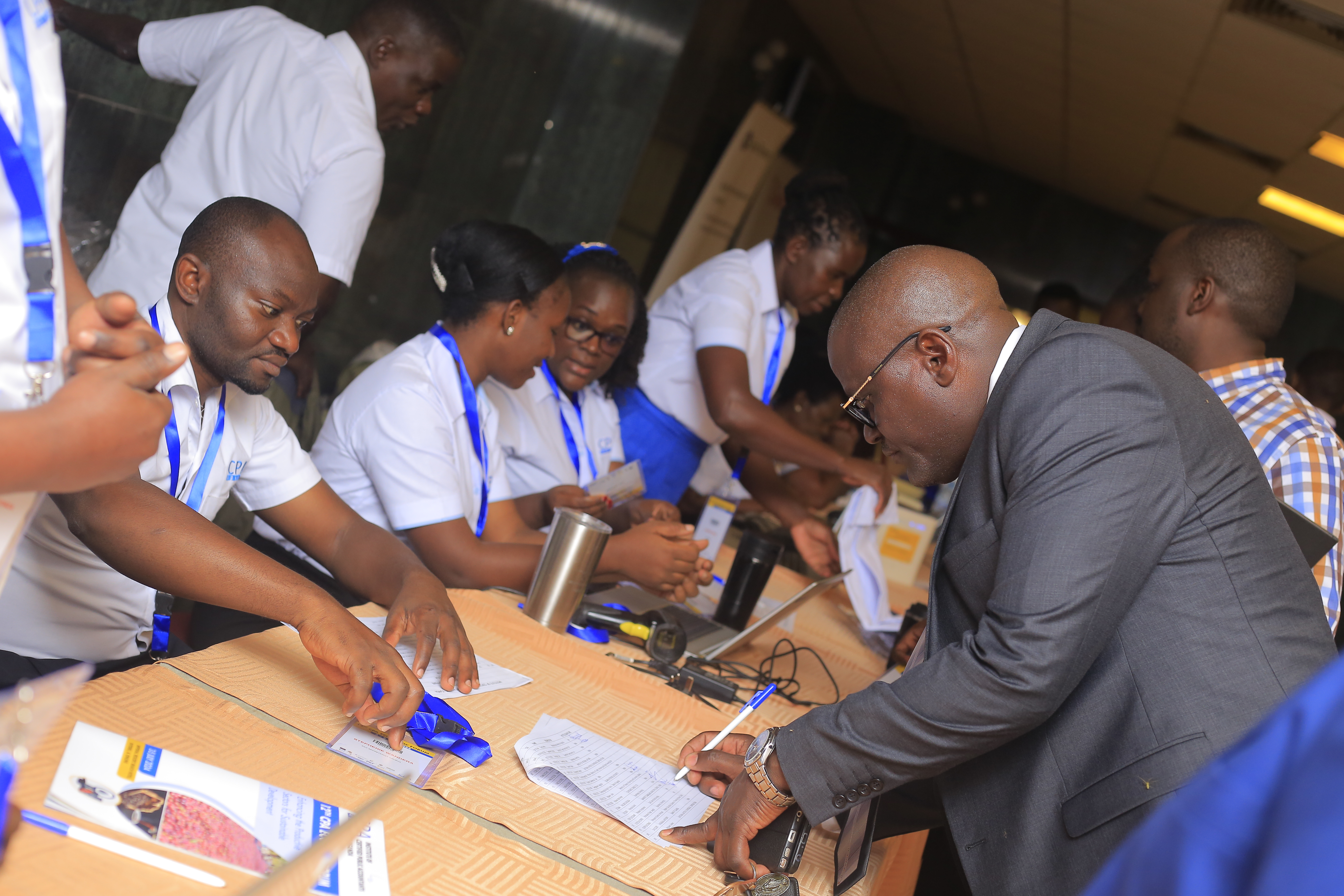 Attendees signing in at the registration desk, with staff assisting and welcoming them.