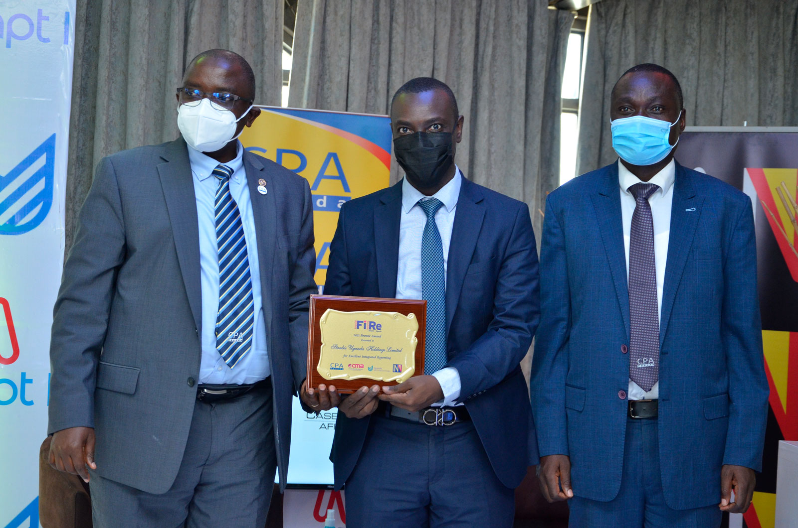 Stanbic Holding's CPA Ronald Makata(C) receives the Gold award on behalf of the bank